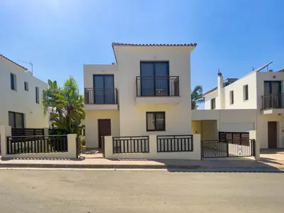 a large white building with balconies on a street at Fotini Villas in Protaras