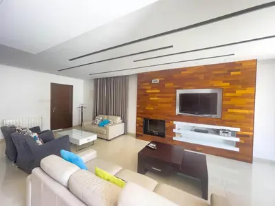a living room with a couch and a tv on a wall at Fotini Villas in Protaras