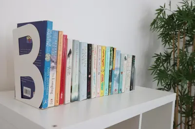 a row of books sitting on a white shelf at Pageant Homes in Nicosia