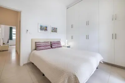a white bedroom with a bed and white cabinets at Pageant Homes in Nicosia