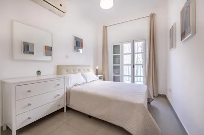 a white bedroom with a white bed and a window at Pageant Homes in Nicosia