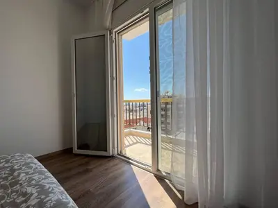 a bedroom with a large glass door to a balcony at Sunny Rooms in Limassol