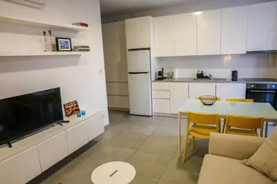 a kitchen with white cabinets and a table with a tv at Luxury Stay in Engomi