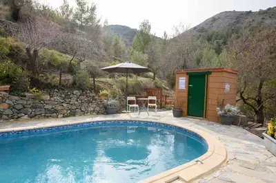 a swimming pool in a yard with a building and an umbrella at Fikardou Chalets in Phikardhou