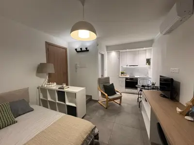 a bedroom with a bed and a desk and a kitchen at Cityscape Urban Apts in Nicosia