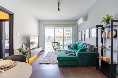 a living room with a green couch and a table at Harbor Apartments in Larnaca in Larnaka