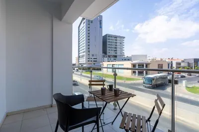 a balcony with a table and chairs and a view of a city at Harbor Apartments in Larnaca in Larnaka