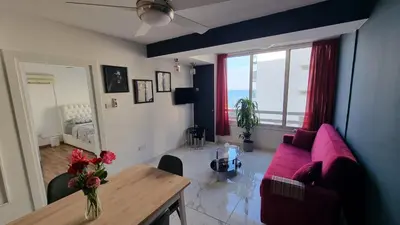 a living room with a pink couch and a table at Stylish Beach Apt w/ Sea View + Pool + 200Mbit in Larnaka
