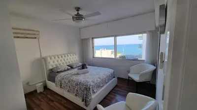 a bedroom with a bed and a large window at Stylish Beach Apt w/ Sea View + Pool + 200Mbit in Larnaka