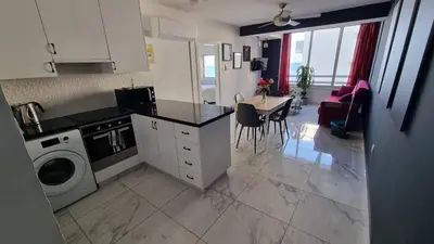 a kitchen with a washing machine and a table with chairs at Stylish Beach Apt w/ Sea View + Pool + 200Mbit in Larnaka
