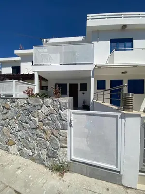 a white house with a stone wall at Green Bay Area Apartment in Protaras