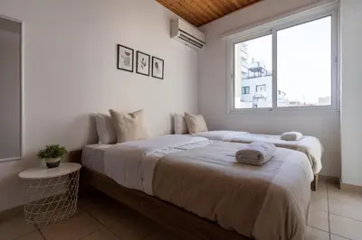 two beds in a white room with a window at Laurel 2-Bedroom Apartment in Larnaca in Larnaka
