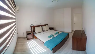 a bedroom with a bed and a dresser and a window at Cozy Apartment In Kapparis in Paralimni