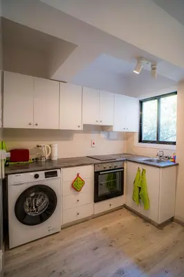 a kitchen with white cabinets and a washer at Cozy Apartment In Kapparis in Paralimni
