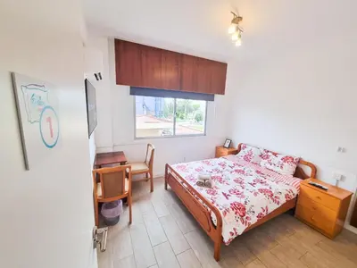 a bedroom with a bed and a desk and a window at Larnaca Garden Rooms in Larnaka