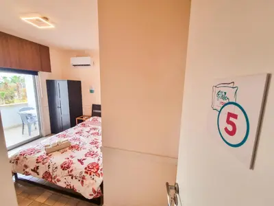 a bedroom with a bed and a room with a window at Larnaca Garden Rooms in Larnaka