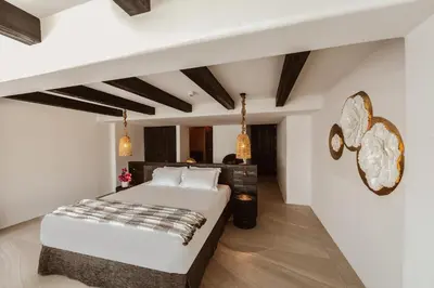 a bedroom with a large white bed and wooden floors at Kaliva Suites - Adults Only in Ayia Napa