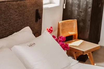 a bedroom with a bed and a chair and flowers at Kaliva Suites - Adults Only in Ayia Napa