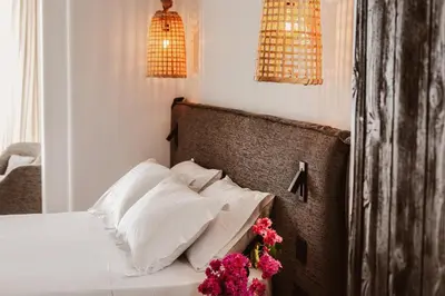 a bedroom with a bed with white pillows and pink flowers at Kaliva Suites - Adults Only in Ayia Napa