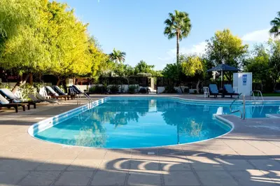 a swimming pool in a resort with chairs and trees at Limassol Star 21 in Limassol