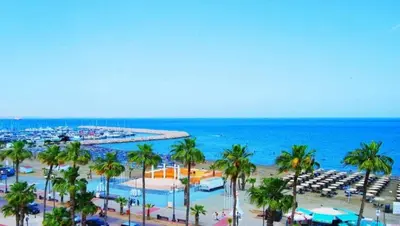 a view of a beach with palm trees and the ocean at Quattro Beachfront Sea View Ap 206 in Larnaka
