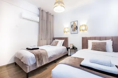 two beds in a bedroom with white walls and wood floors at Quattro Beachfront Sea View Ap 206 in Larnaka
