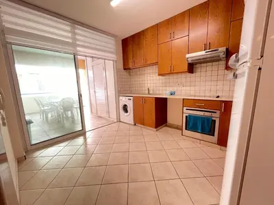 a kitchen with wooden cabinets and a view of a patio at Anastasia Holiday Apartment Larnaca in Larnaka