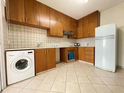 a kitchen with wooden cabinets and a washer and dryer at Anastasia Holiday Apartment Larnaca in Larnaka