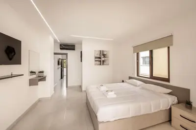 a white bedroom with a large bed and a window at SEVIS SUITES in Ayia Napa