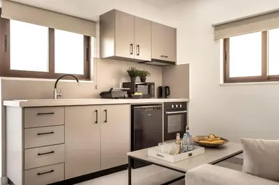 a kitchen with white cabinets and a coffee table at SEVIS SUITES in Ayia Napa