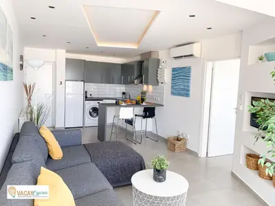 a living room with a blue couch and a kitchen at Sea the Sunrise in Larnaka