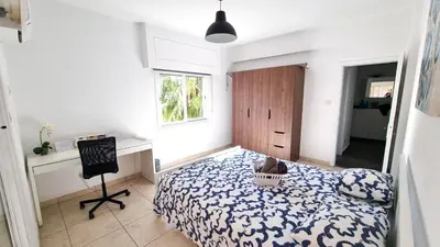 a bedroom with a bed and a desk and a chair at Center 2Br Apt w/ parking and 250m walk from beach in Larnaka
