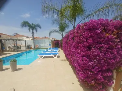 a hedge of purple flowers next to a swimming pool at Villa Niki in Ayia Napa