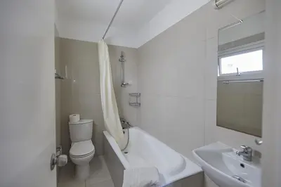a white bathroom with a toilet and a sink at Napa Hera 's Nest in Ayia Napa