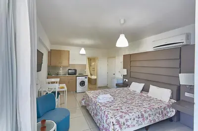 a bedroom with a bed and a blue chair at Napa Hera 's Nest in Ayia Napa