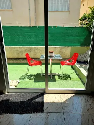 two red chairs and a table outside a window at Μοναδικό δωμάτιο in Limassol