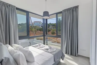 a white bedroom with a bed and a large window at Protaras Elite Pearl Ville Ep3c in Protaras