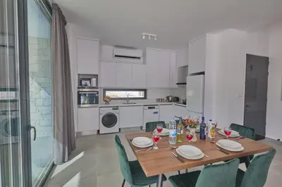 a kitchen with a wooden table and green chairs at Protaras Elite Pearl Ville Ep3c in Protaras