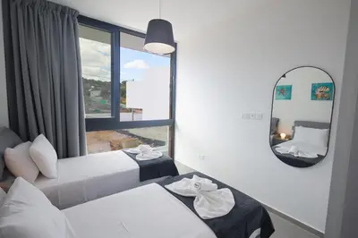 a bedroom with two beds and a mirror and a window at Protaras Elite Pearl Ville Ep3c in Protaras