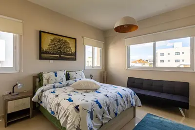 a bedroom with a bed and a couch and two windows at Central Bliss / your perfect home away from home in Limassol