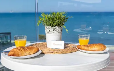 a table with two plates of croissants and orange juice at Seaview Apartment (Excellent Location) in Larnaka