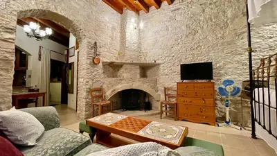 a living room with a stone wall with a fireplace at Juliet Suite by TrulyCyprus in Doros