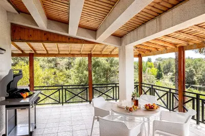 a patio with a table and chairs and a grill at Platres Forest Panorama Cottage in Platres