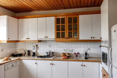 a kitchen with white cabinets and a wooden ceiling at Platres Forest Panorama Cottage in Platres