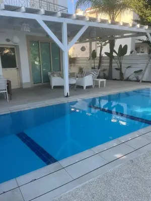 a blue swimming pool with a pergola at Riverland Turtle Beach Villa-1min walk to beach in Protaras