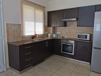 a kitchen with black cabinets and a sink and a microwave at Mythical Sands BG03 townhouse in Paralimni