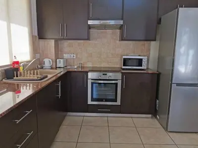 a kitchen with brown cabinets and a stove and a microwave at Mythical Sands BG03 townhouse in Paralimni