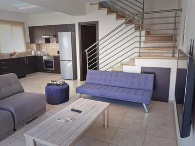 a living room with a couch and a table and stairs at Mythical Sands BG03 townhouse in Paralimni