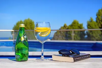 a glass of wine next to a book and a bottle at Villa Sea Horizon in Protaras