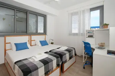 a bedroom with two beds with blue pillows and a desk at Villa Sea Horizon in Protaras